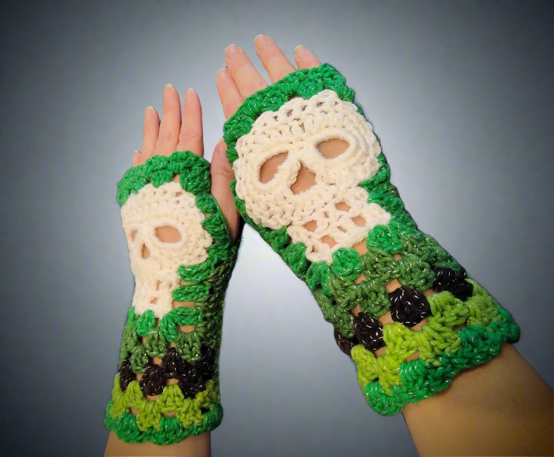 A pair of fingerless gloves featuring a floral and skull pattern in green, black, and white colors.