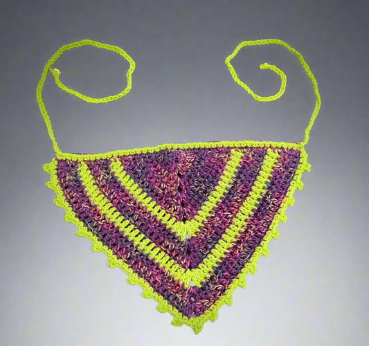 A multicolored geometric patterned bandana with prominent purple and green colors, laid flat on a dark surface.